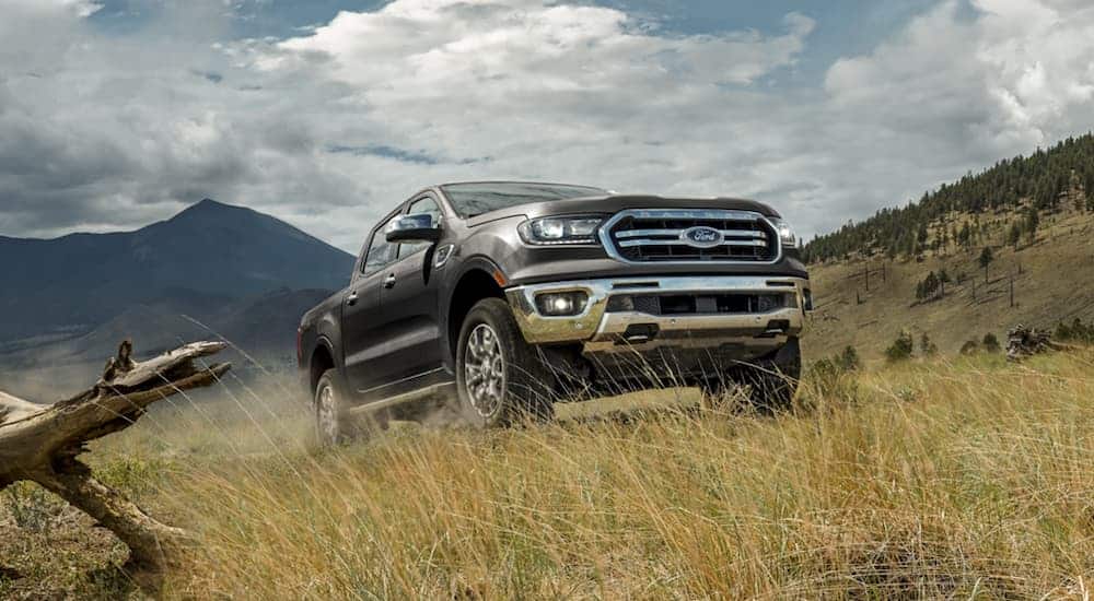 A dark grey 2020 Ford Ranger is driving in a field in front of mountains.