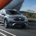 A grey 2020 Honda CR-V is driving on a modern bridge.