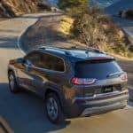 A gray 2020 Jeep Cherokee is driving on an empty highway.