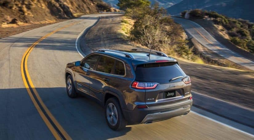 A gray 2020 Jeep Cherokee is driving on an empty highway.
