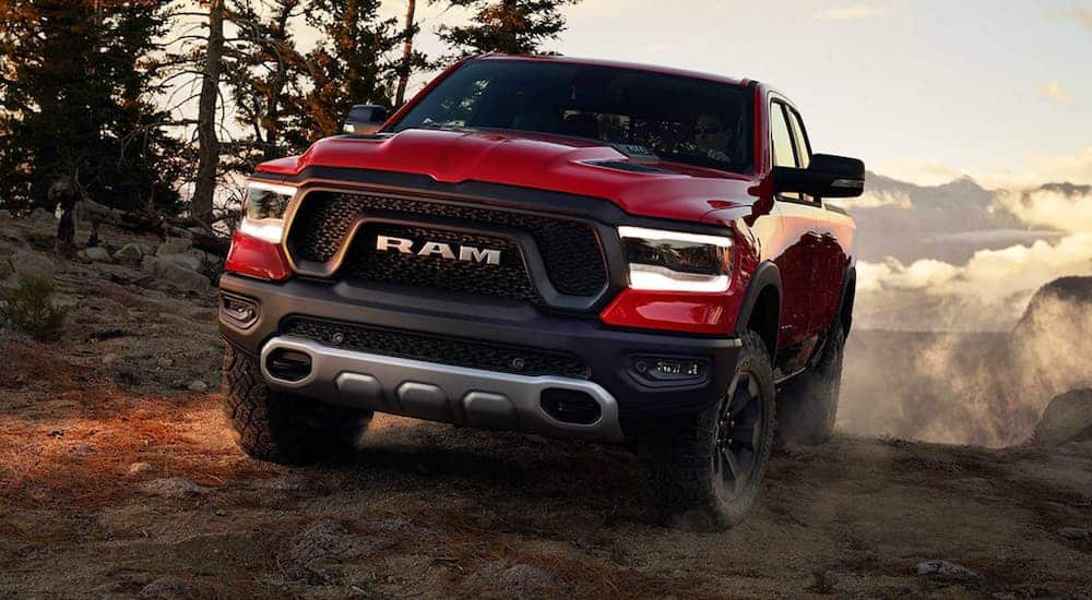 A red 2020 Ram 1500 Rebel is off-roading a dirt trail in the woods.