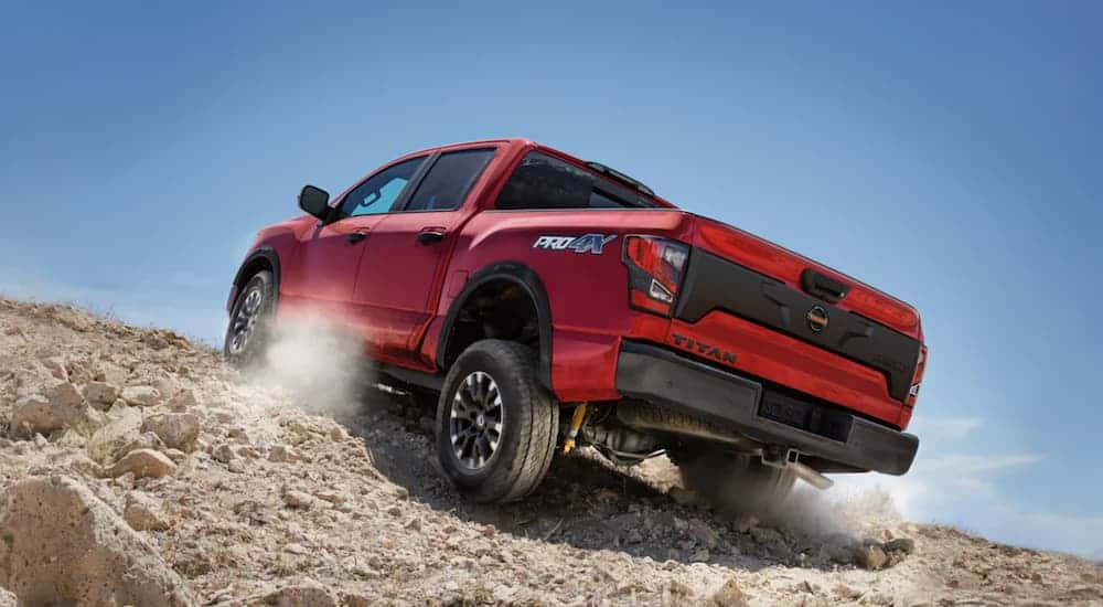 A red 2020 Nissan Titan is off-roading up a dirt hill.