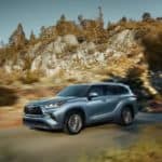 A grey 2020 Toyota Highlander is driving on a mountain road.