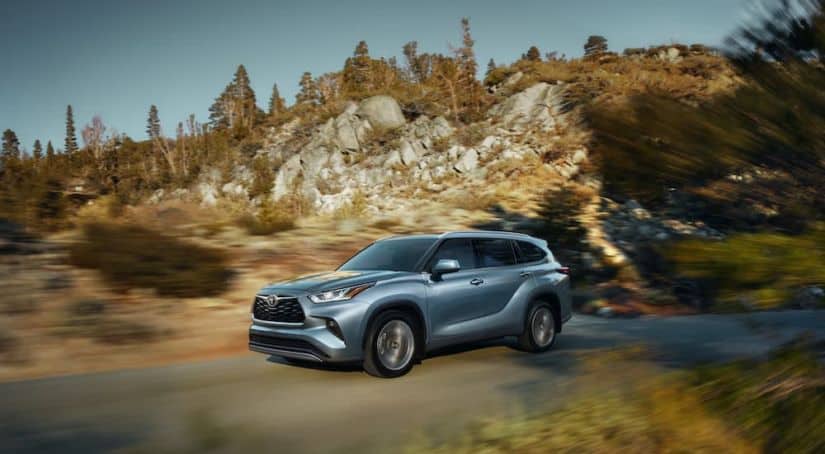 A grey 2020 Toyota Highlander is driving on a mountain road.