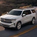 A white 2021 Chevy Suburban is driving on a winding mountain road.