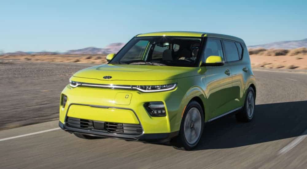 A green 2021 Kia Soul EV is driving on a desert road.