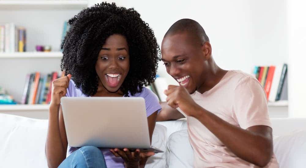 A young couple is excited about buying a car online.