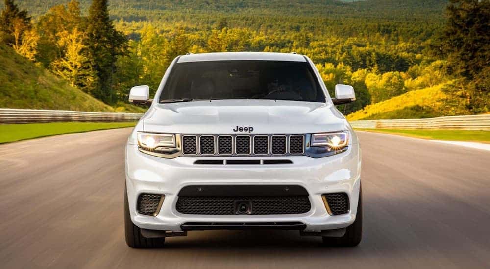 A white 2020 Jeep Grand Cherokee Trackhawk is shown from the front driving on a racetrack.