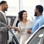 A salesman is showing a smiling couple a car in an Ohio car dealer showroom.