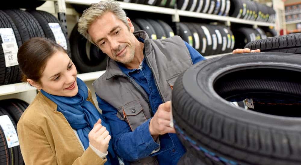 Мужчина и женщина проверяют шины в шиномонтажной мастерской.