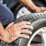 A closeup is shown of hands changing a tire.