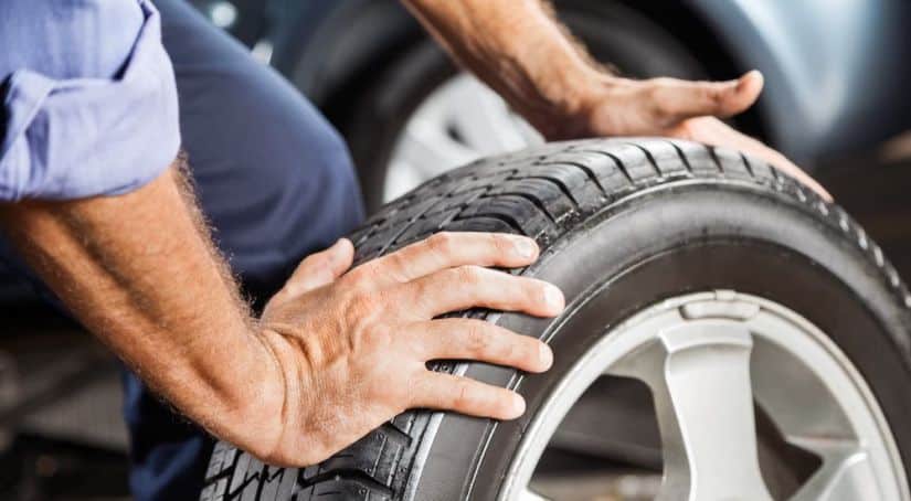 A closeup is shown of hands changing a tire.