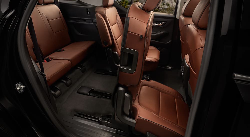 The brown interior of a 2020 Chevy Traverse is shown with the middle row seat folding forward.