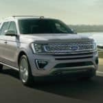 A silver 2020 Ford Expedition is driving past an ocean bay after winning the 2020 Ford Expedition vs 2020 GMC Yukon comparison.