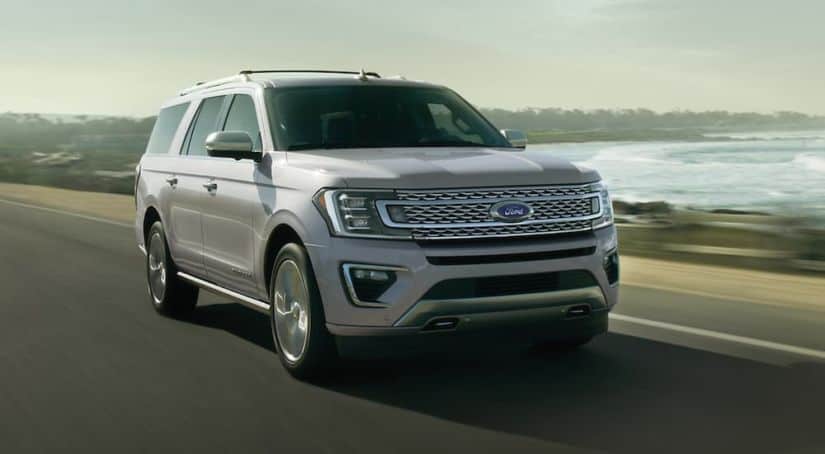 A silver 2020 Ford Expedition is driving past an ocean bay after winning the 2020 Ford Expedition vs 2020 GMC Yukon comparison.