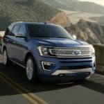 A blue 2020 Ford Expedition is driving along a cliff next to the ocean.