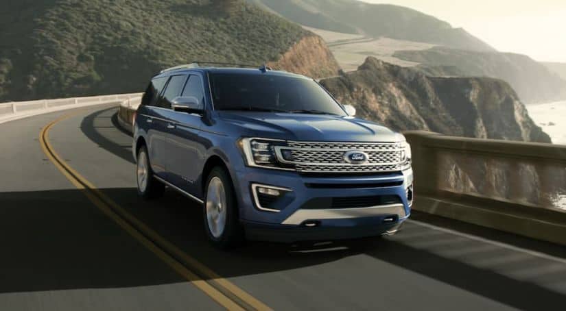 A blue 2020 Ford Expedition is driving along a cliff next to the ocean.