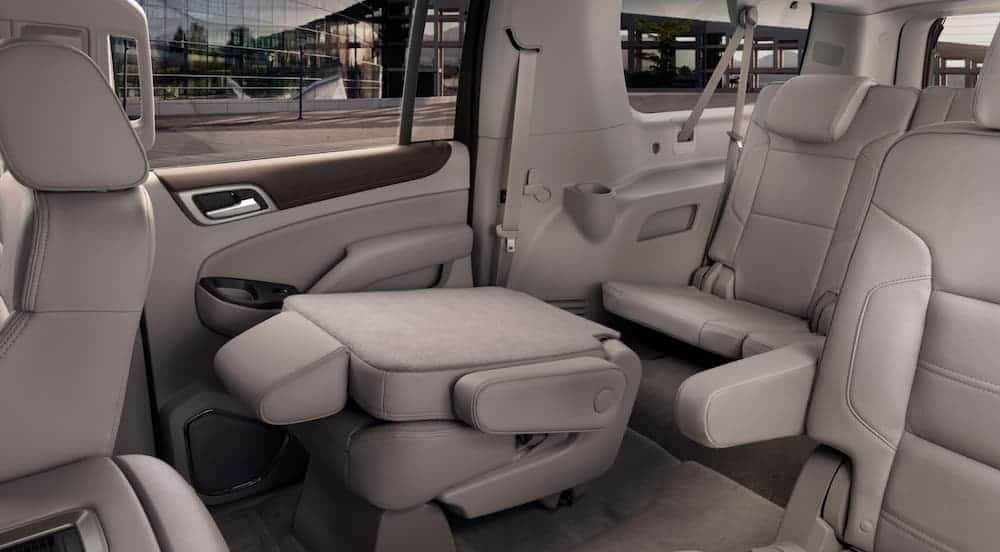 The middle row seat is folded down in the off-white interior of a 2020 GMC Yukon.