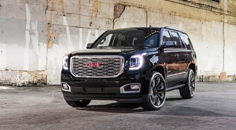 A black 2020 GMC Yukon Denali is parked in front of a concrete wall after winning the 2020 GMC Yukon vs 2020 Ford Expedition comparison.