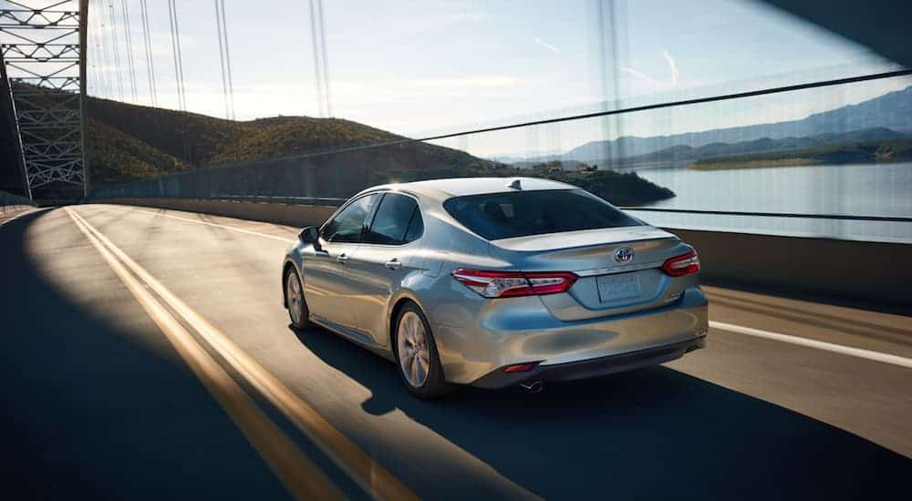 A silver 2020 Toyota Camry is driving on a bridge over a body a work.