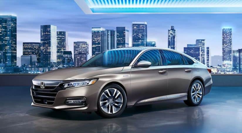 A tan 2020 Honda Accord is parked in front of a city at night after winning the 2020 Honda Accord vs 2020 Toyota Camry comparison.