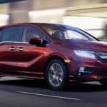 A red 2020 Honda Odyssey is driving on a covered highway.