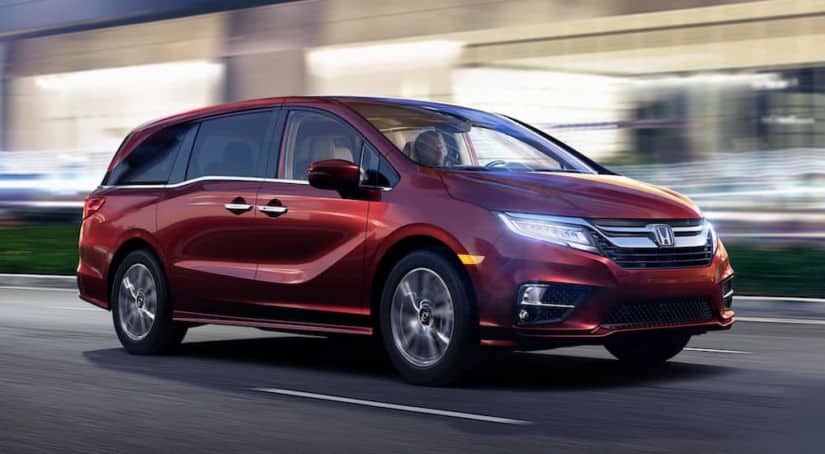 A red 2020 Honda Odyssey is driving on a covered highway.