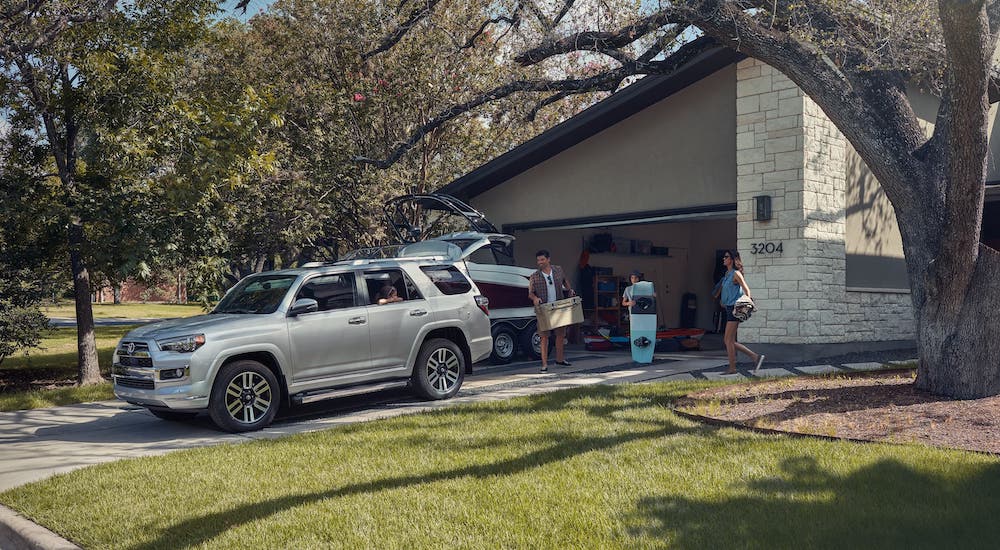 A family is loading gear into a silver 2020 Toyota 4Runner that is parked in a driveway.