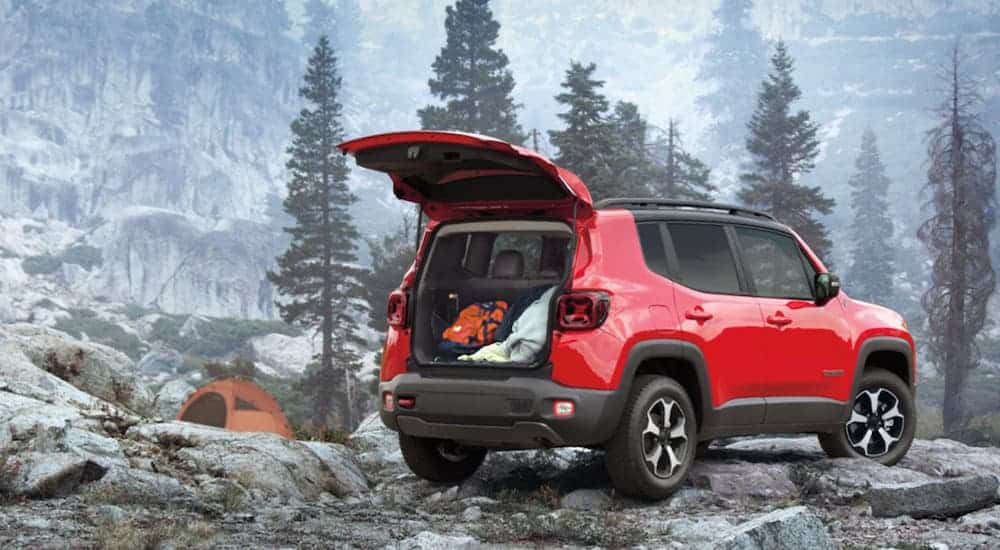 A red 2020 Jeep Renegade is at a campsite on a misty mountain.