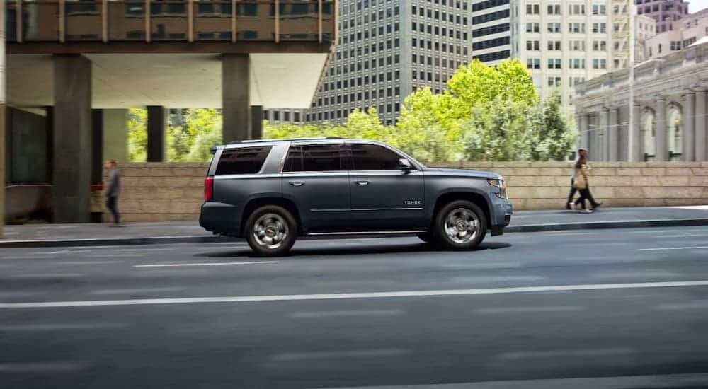 A gray 2020 Chevy Tahoe is shown from the side while driving in a city.