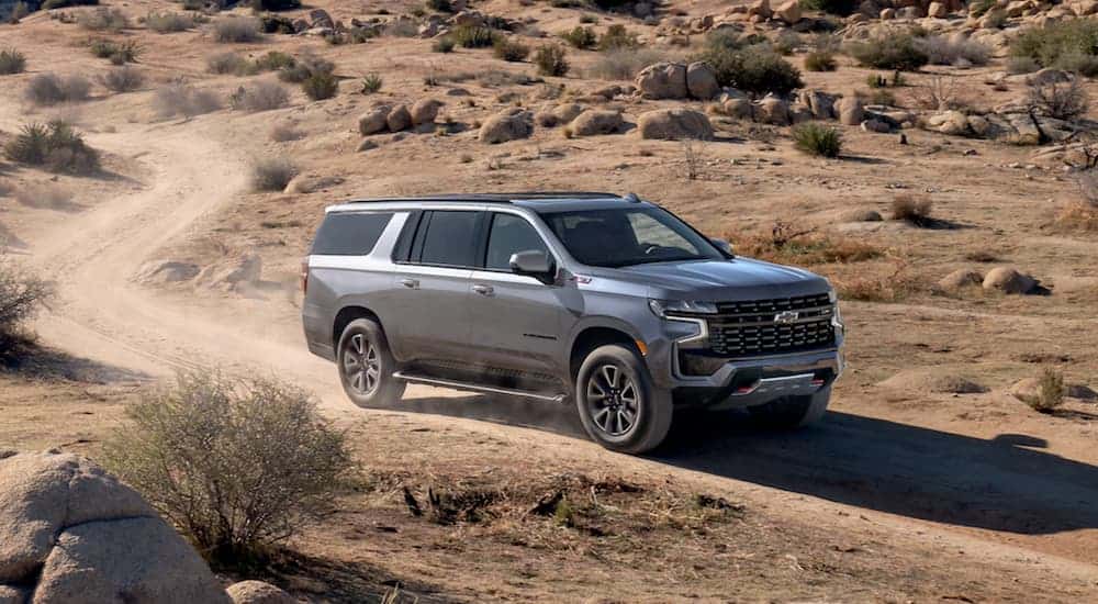 A grey 2021 Chevy Suburban is driving on a desert dirt road.