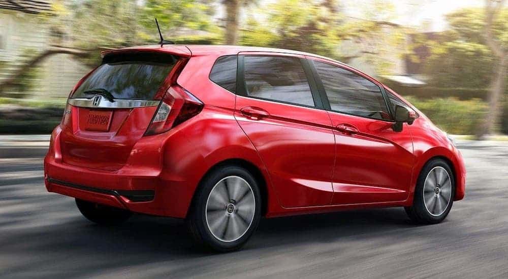 A red 2020 Honda Fit EX-L from a Honda dealer near you is driving on a suburban road.