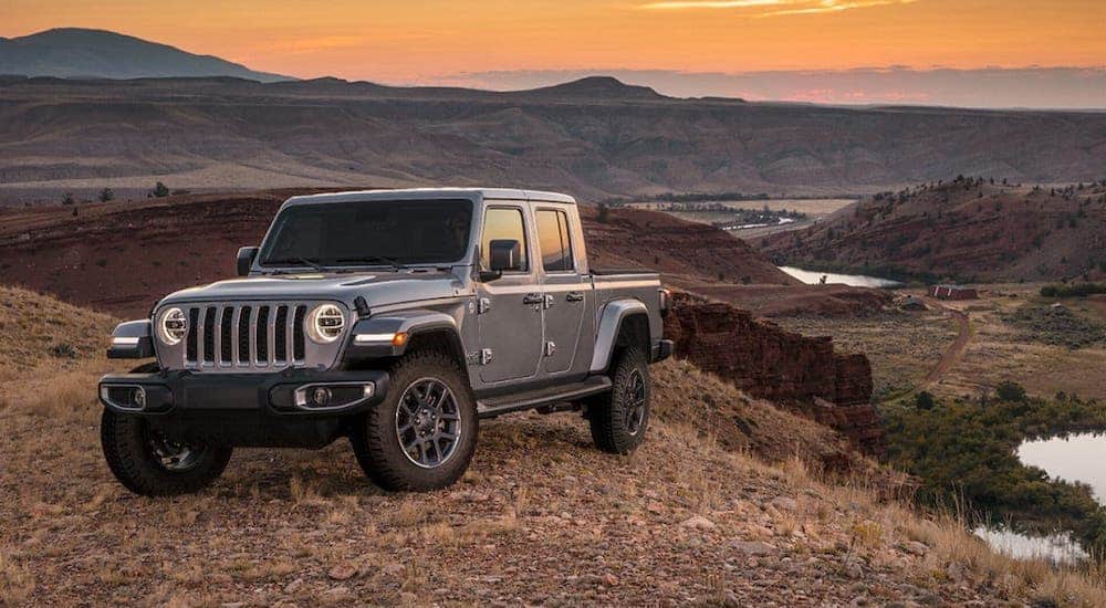 A silver 2020 Jeep Gladiator is parked on a hill in front of a desert.