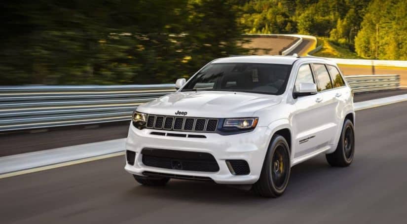 A white 2020 Jeep Grand Cherokee Trackhawk is driving on a track.