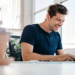 A man is smiling while looking at an online car dealership.