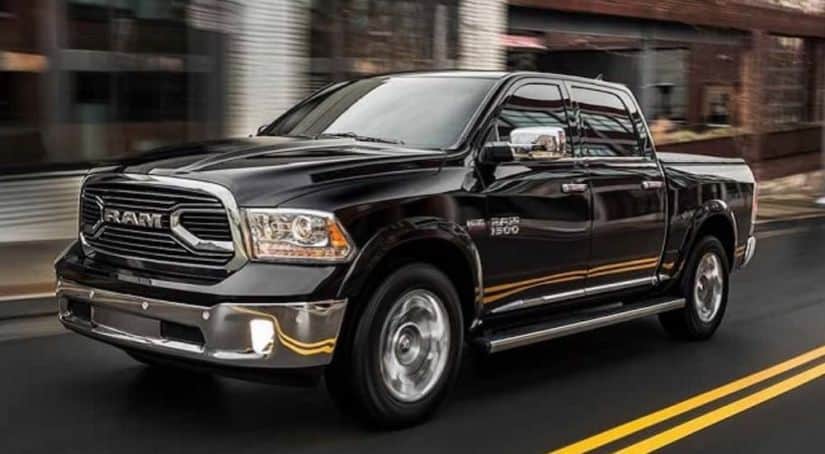 A black 2018 Ram 1500 is driving on a city street after leaving a used car dealership near me.