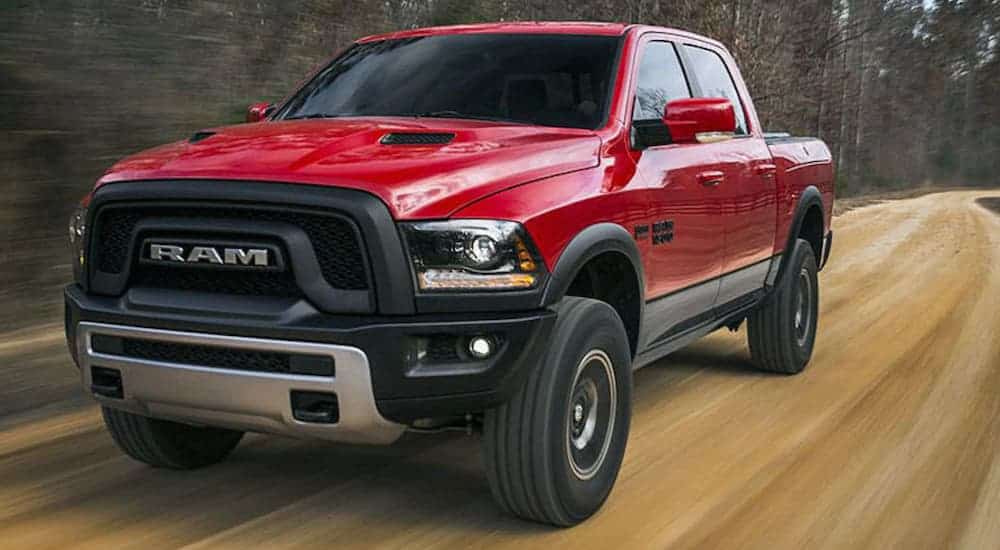A red 2018 Ram 1500 Rebel is driving on a dirt road.