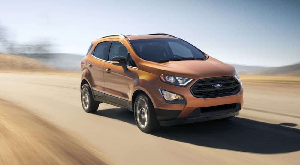 An orange 2020 Ford EcoSport is driving on a blurred desert road.
