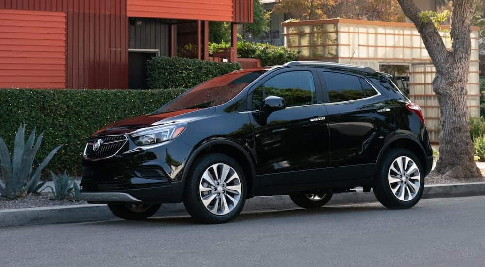 A black 2020 Buick Encore is parked in front of a red building.