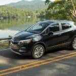 A black 2020 Buick Encore is driving past a lake after winning the 2020 Buick Encore vs 2020 Nissan Kicks comparison.