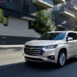 A white 2020 Chevy Traverse is driving on a city street.