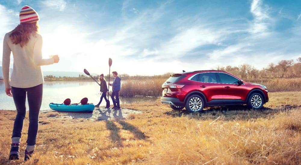 One of the best SUVs, a red 2020 Ford Escape, is parked next to a pond and people about to kayak.