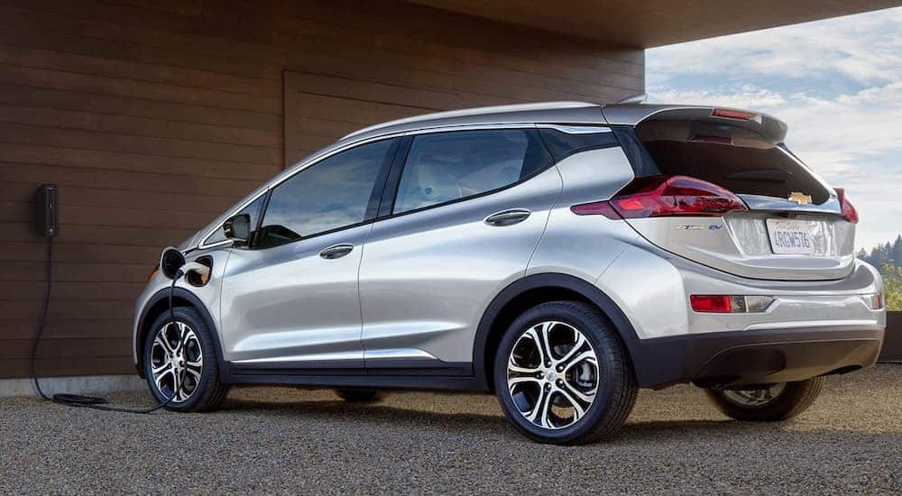 A silver 2020 Chevy Bolt EV is plugged into a modern home.