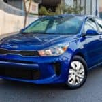 A blue 2020 Kia Rio is parked on a city street.