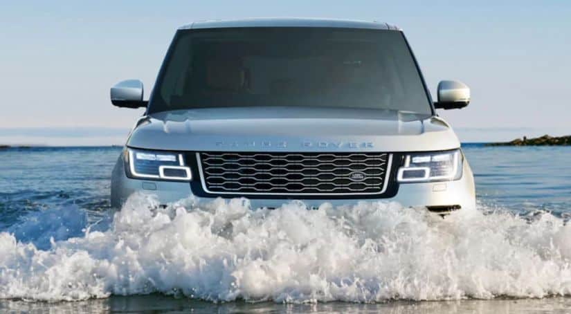 A silver 2020 Land Rover Ranger Rover is driving through deep water, shown from the front.