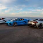 A white, a blue and a silver 2021 Chevy Corvette Stingray are parked in front of an ocean.