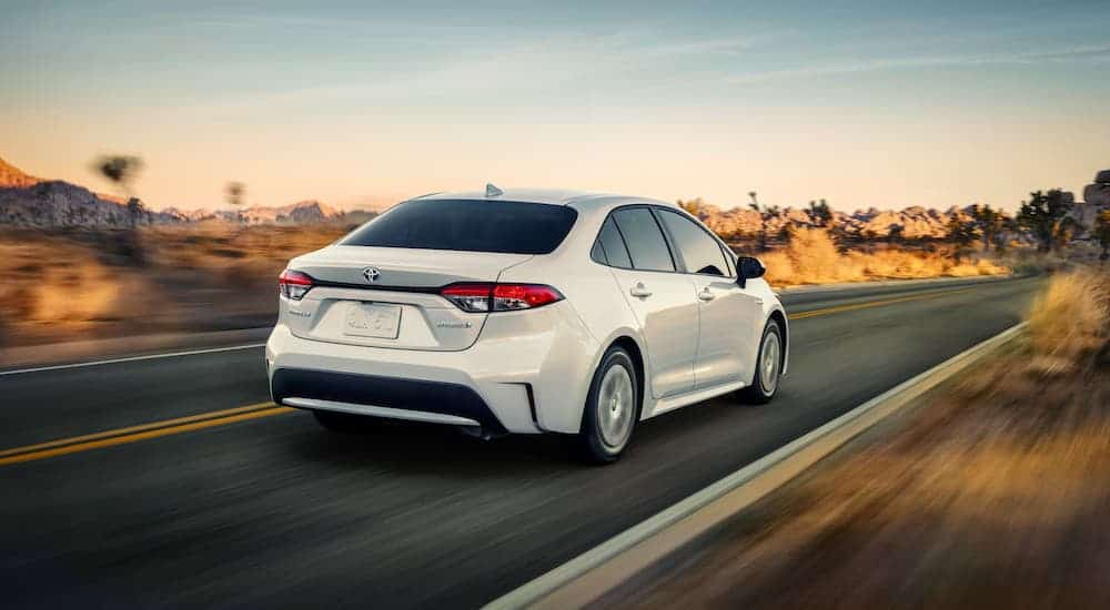 A white 2020 Toyota Corolla Hybrid is driving on a highway after leaving a Toyota dealership near you.