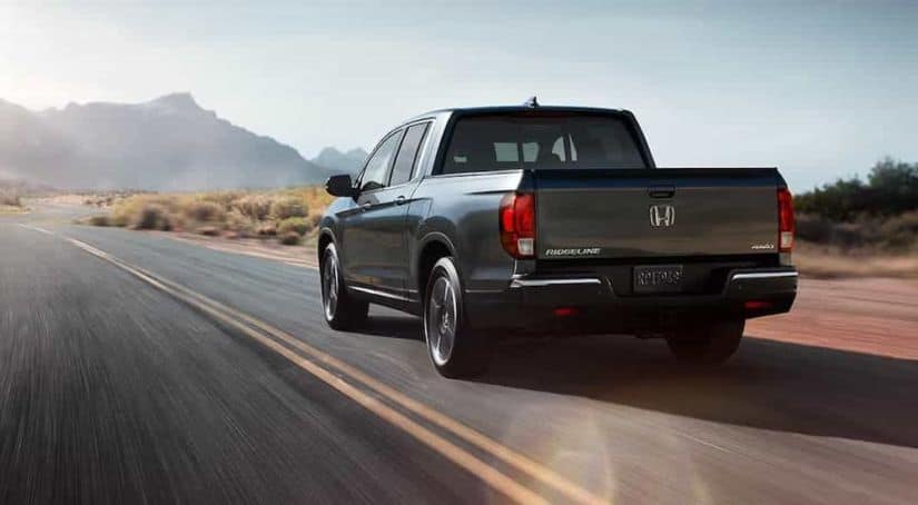 A gray 2019 Honda Ridgeline is driving away on a desert highway.