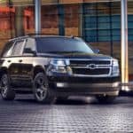 A black 2017 Chevy Tahoe is parked in front of a modern building at night.
