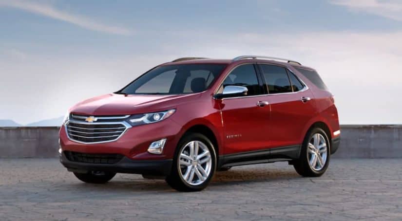 A red 2020 Chevy Equinox is parked in front of a low cement wall and sky after winning the 2020 Chevy Equinox vs 2020 Nissan Rogue comparison.